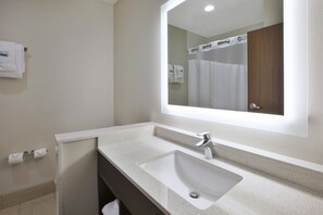 Un baño moderno con un espejo grande, un lavabo y una zona de ducha.