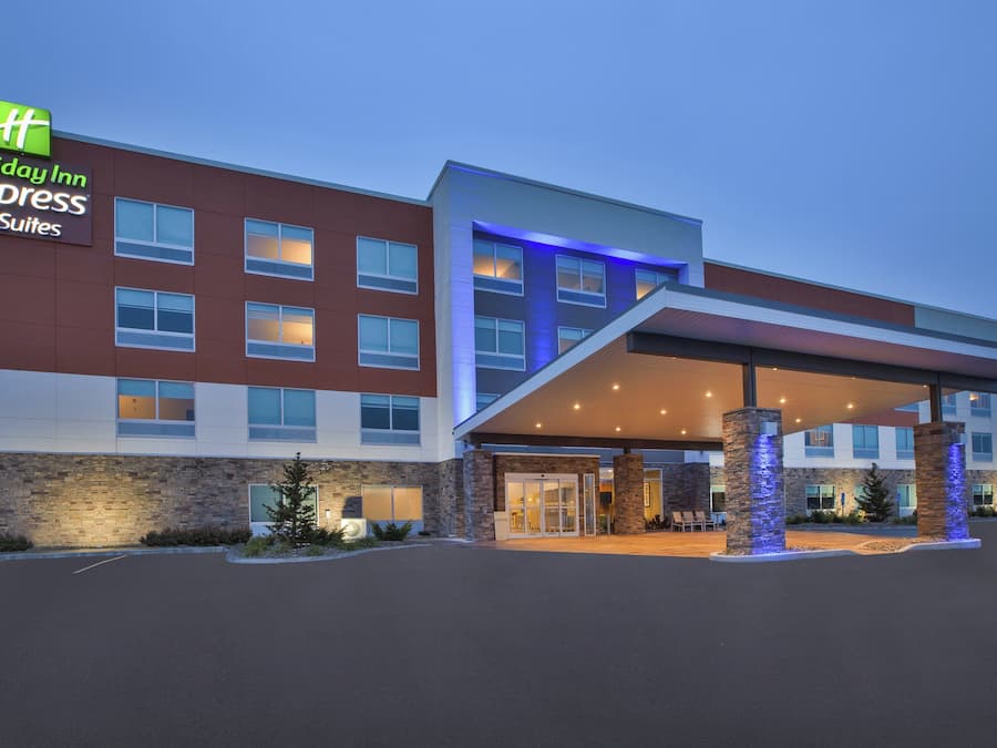 A Holiday Inn Express & Suites hotel with a modern design, featuring a covered entrance and stone accents.