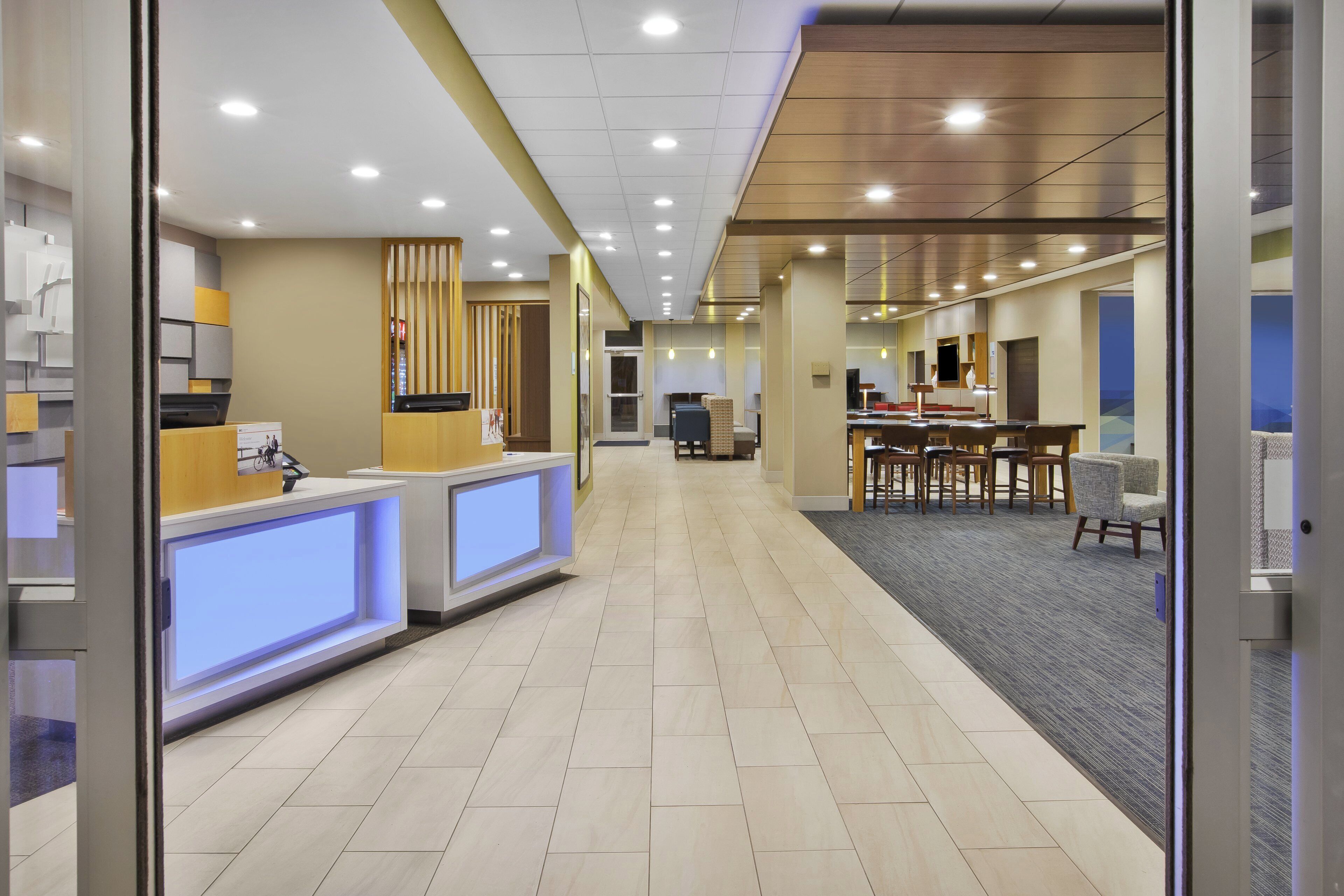 A hotel reception area with a reception desk, a waiting area with chairs, and a counter with a computer.