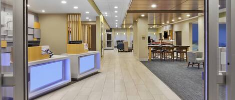 A hotel reception area with a reception desk, a waiting area with chairs, and a counter with a computer.