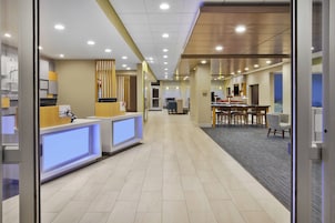 Zona de recepción de hotel con mostrador de recepción, área de espera con sillas y un mostrador con una computadora.
