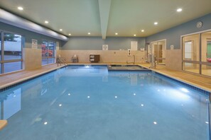 A swimming pool with a tiled deck, a lifeguard chair, and a sauna area. - Holiday Inn Express & Suites Parkersburg East by IHG (Parkersburg)