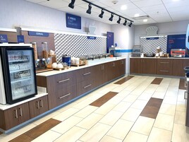 Espaço para refeições com balcão refrigerado para laticínios, balcão para comida quente e uma área de padaria.