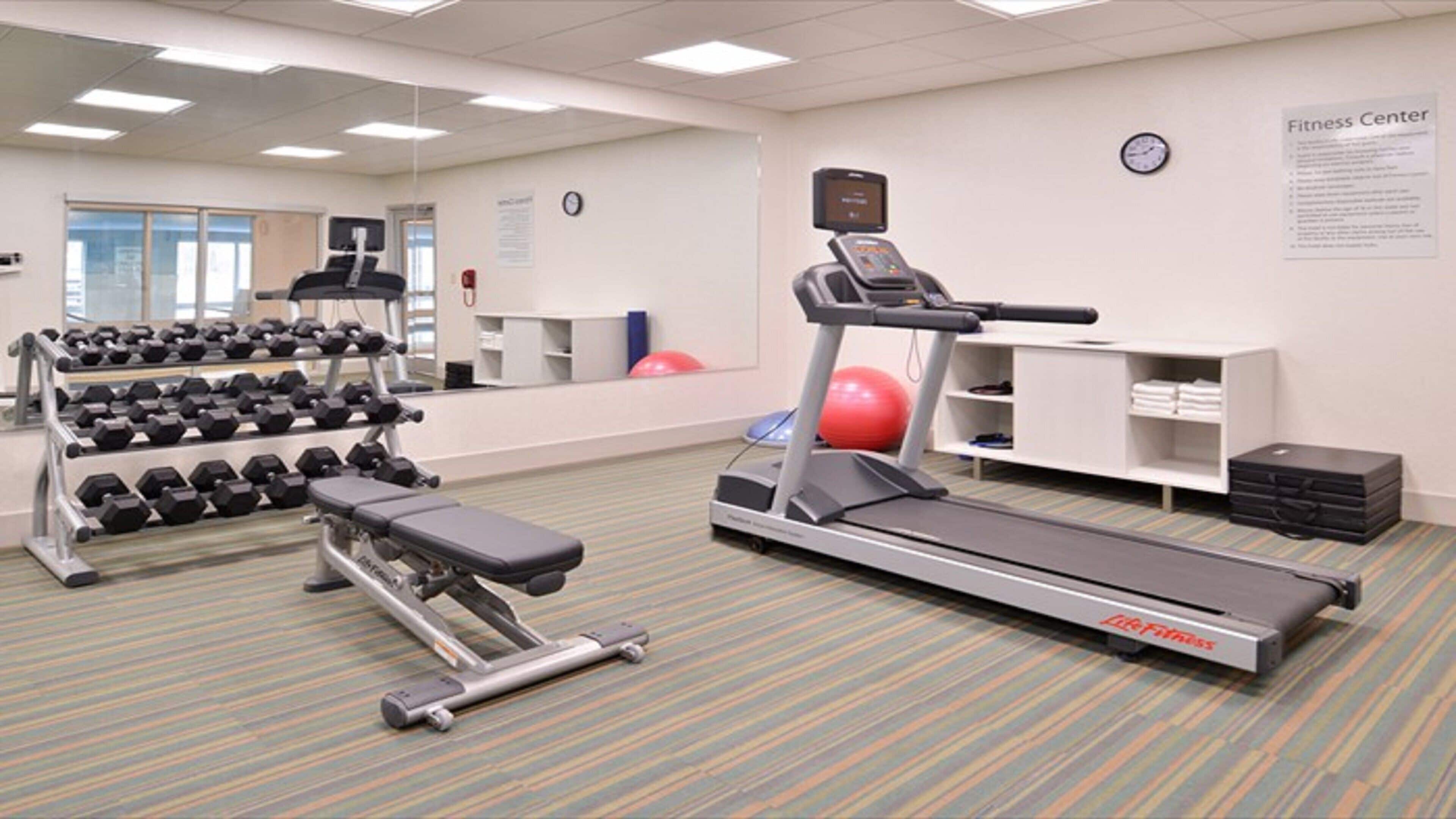 A fitness center with treadmills, dumbbells, and exercise balls.