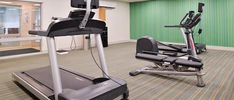 A fitness room with a treadmill and an elliptical machine.