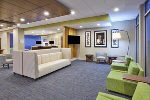 A hotel lobby with seating areas, a reception desk, and a television. - Holiday Inn Express & Suites Parkersburg East by IHG (Parkersburg)