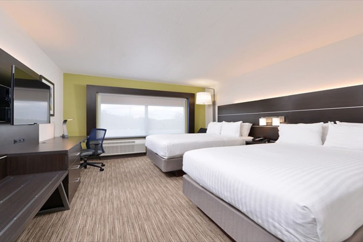 Una habitación de hotel con una cama grande, un escritorio, una silla y un televisor.