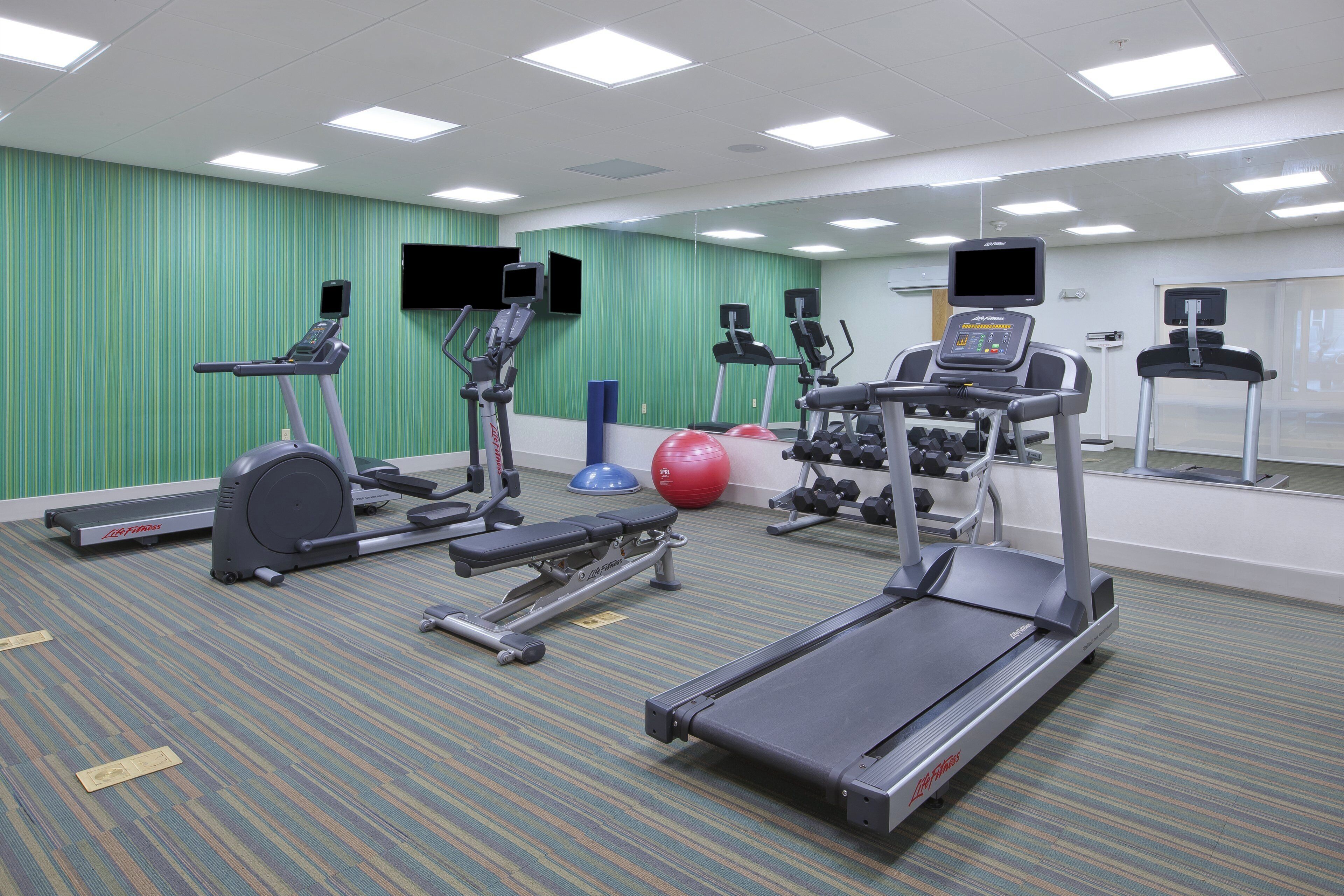 A gym with treadmills, elliptical machines, and free weights.