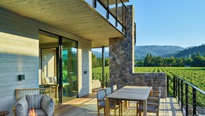 A wooden deck with a fire pit, outdoor seating, and a view of a vineyard. - Alila Napa Valley, a Hyatt Luxury Resort (St. Helena)