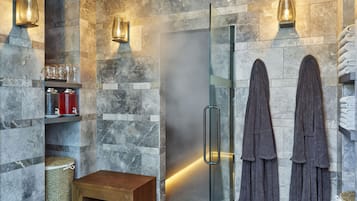 A modern bathroom with a glass shower enclosure, marble walls, and a wooden bench.