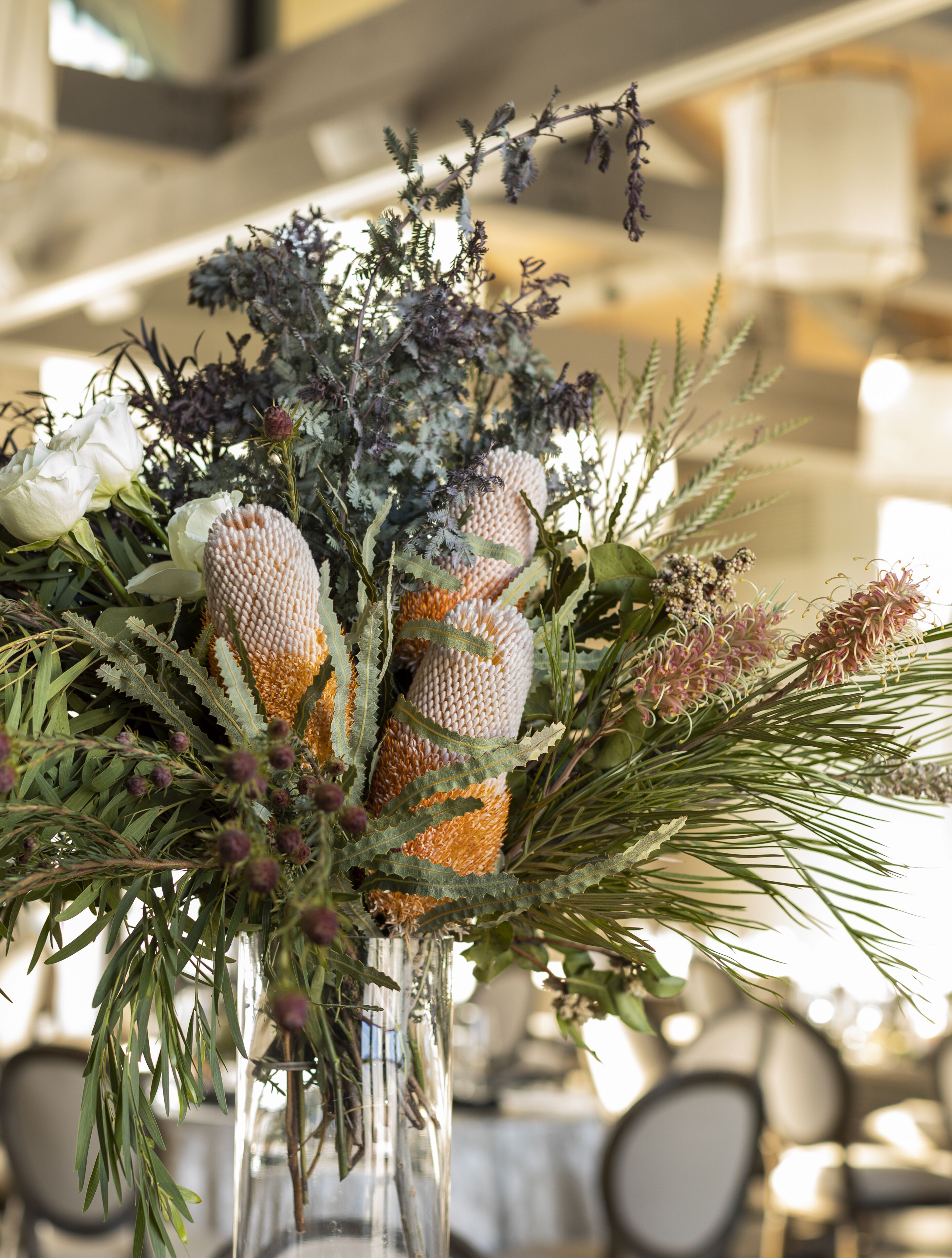A floral arrangement in a clear vase with various plants and flowers.
