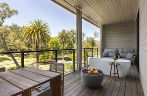 A wooden deck with a fire pit, outdoor seating, and a view of a landscaped garden. - Alila Napa Valley, a Hyatt Luxury Resort (St. Helena)