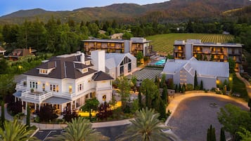A large resort with multiple buildings, a swimming pool, and a vineyard in the background.