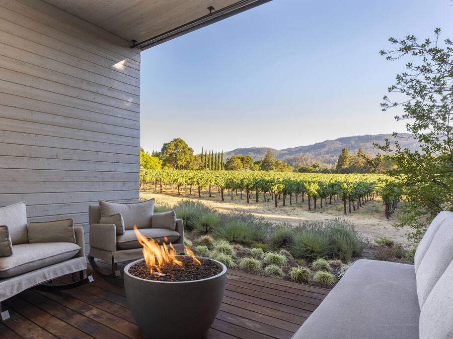 A patio with a fire pit, outdoor furniture, and a vineyard view.