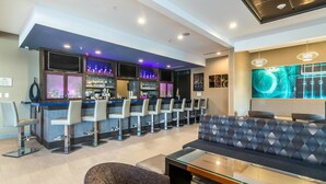 A modern bar area with a long counter, multiple bar stools, and a seating area with a sofa and armchairs. - SpringHill Suites by Marriott Oklahoma City Downtown (Oklahoma City)