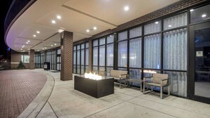 An outdoor seating area with a fire feature, brick walls, and large windows. - SpringHill Suites by Marriott Oklahoma City Downtown (Oklahoma City)