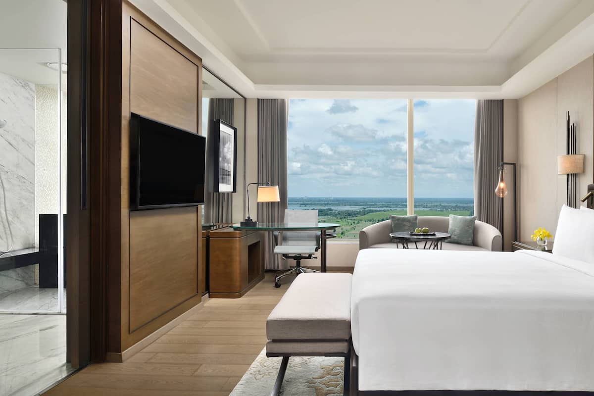 Een hotelkamer met een groot bed, een bureau, een televisie en uitzicht op de oceaan.