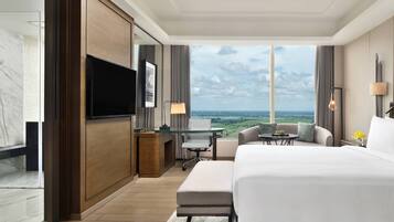 A hotel room with a large bed, a desk, a television, and a view of the ocean.