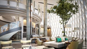 A modern hotel lobby with a curved staircase, seating areas, and a large tree.