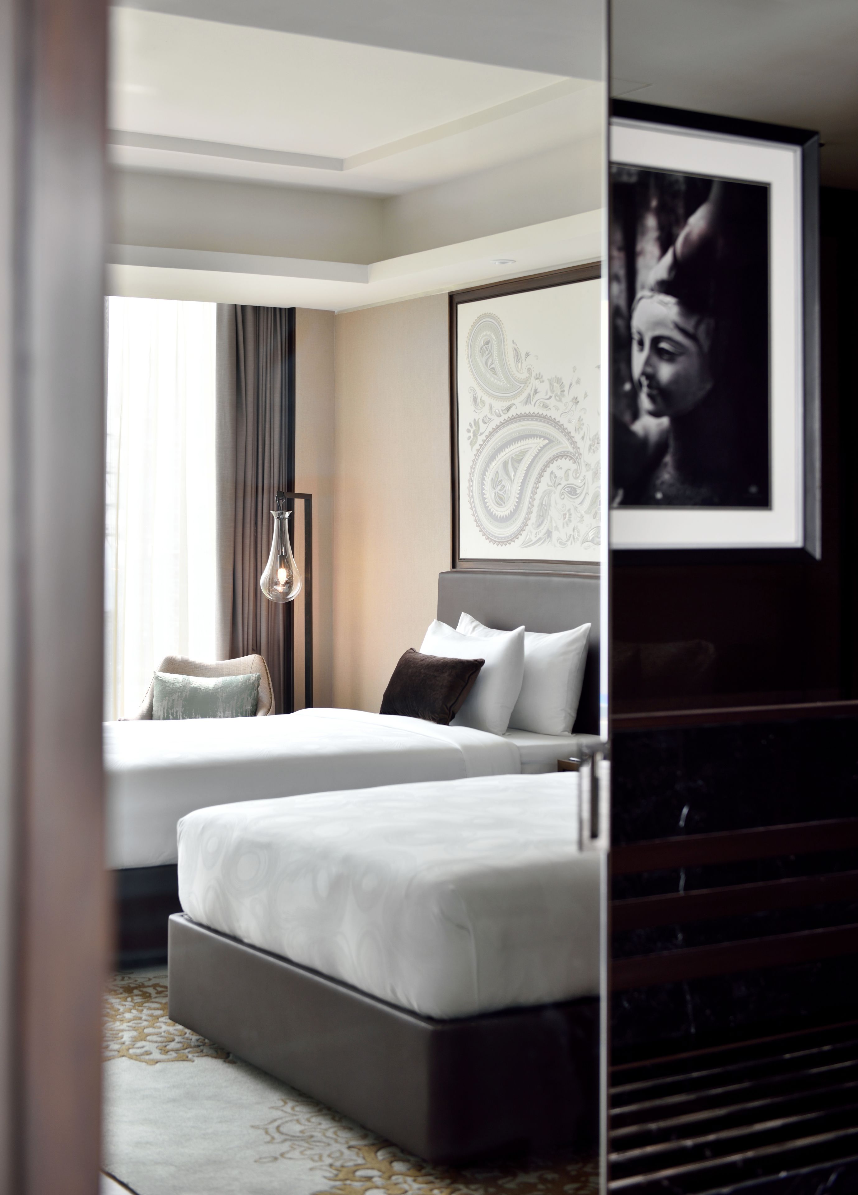 Habitación de hotel con dos camas, un ventanal con cortinas, una obra de arte en la pared y un cuadro enmarcado.