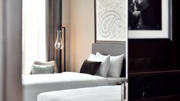 Habitación de hotel con dos camas, un ventanal con cortinas, una obra de arte en la pared y un cuadro enmarcado.