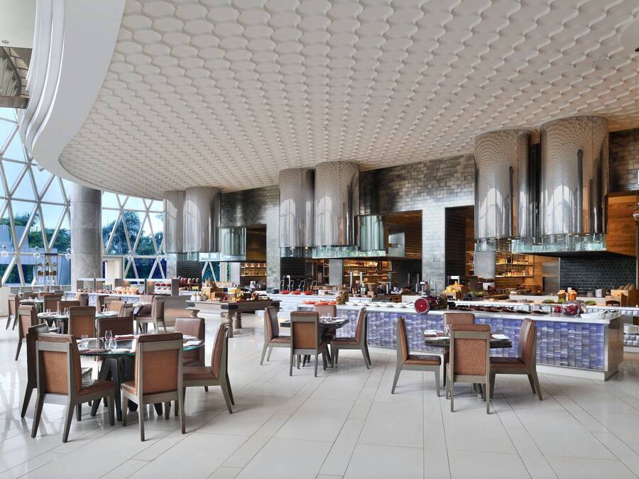 Ruime eetruimte met hoge plafonds en een modern design, met een centraal eiland, een bar en zitplaatsen voor gasten.