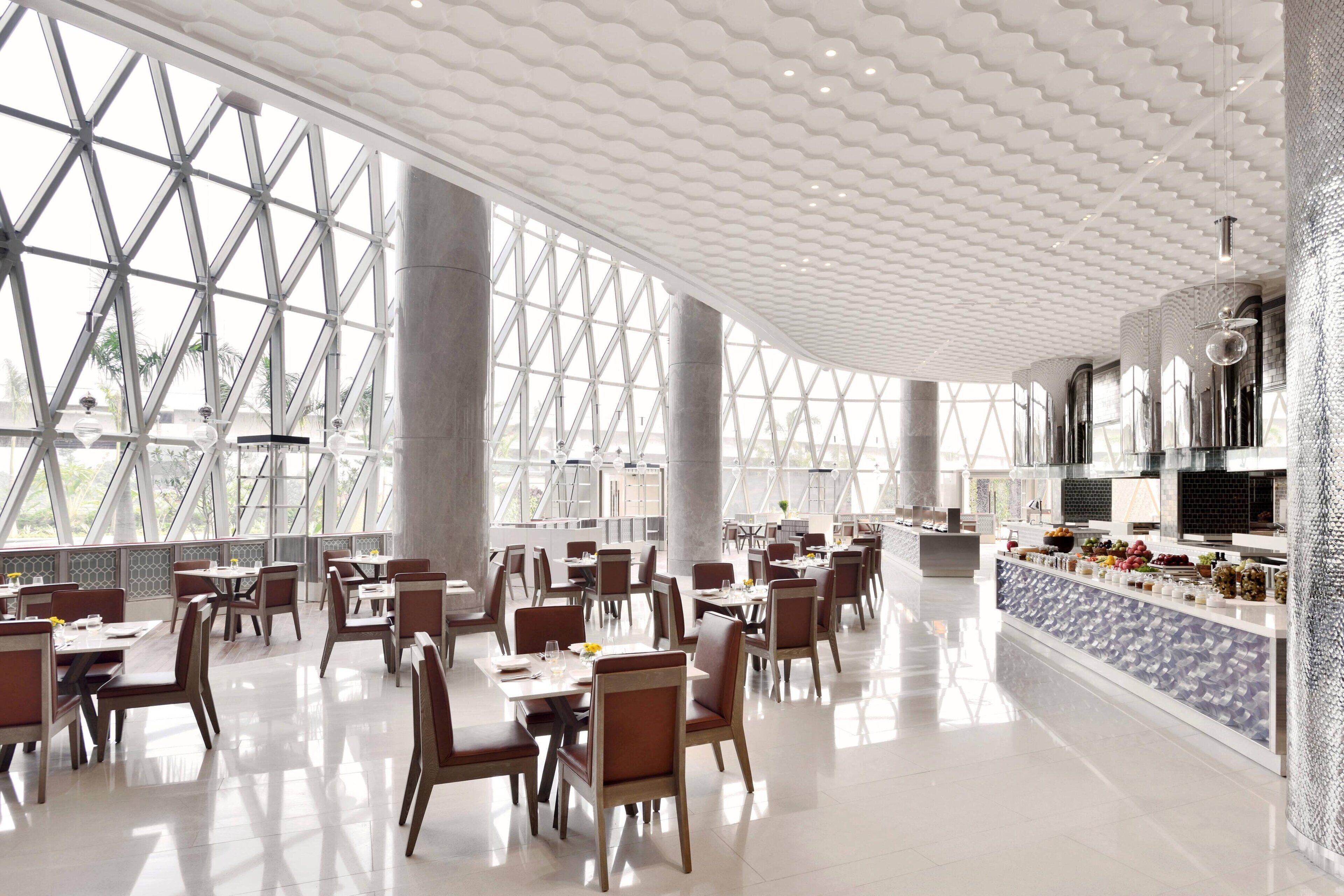 Un vaste espace dédié à la salle à manger, doté de hauts plafonds, de grandes fenêtres et d’un aménagement intérieur moderne.