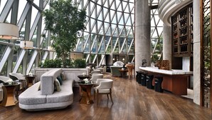 A modern interior with a curved sofa, wooden flooring, and a large glass window structure.