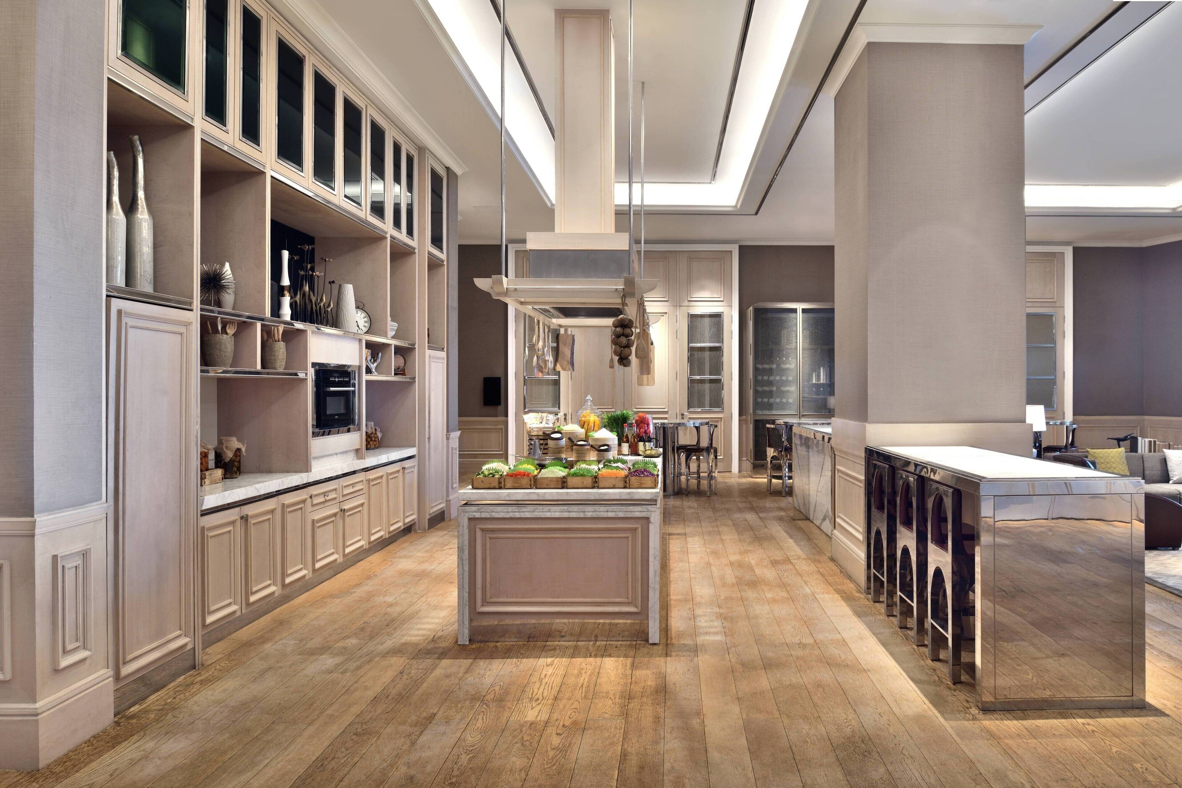 A spacious kitchen with wooden flooring, built-in cabinetry, and a central island with a sink.