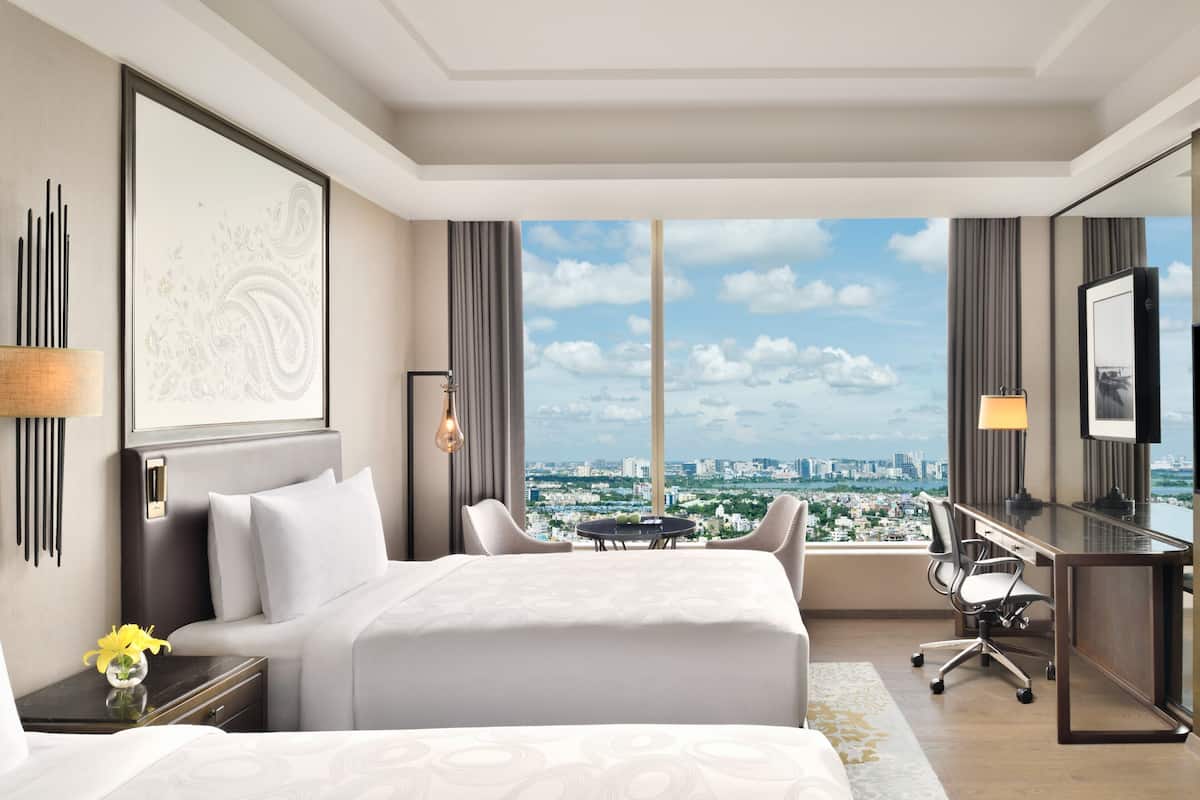 Hotelkamer met een groot bed, een bureau, een stoel, stadszicht en een groot raam.