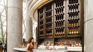 A bar area with a marble countertop, multiple stools, and a large wine display.