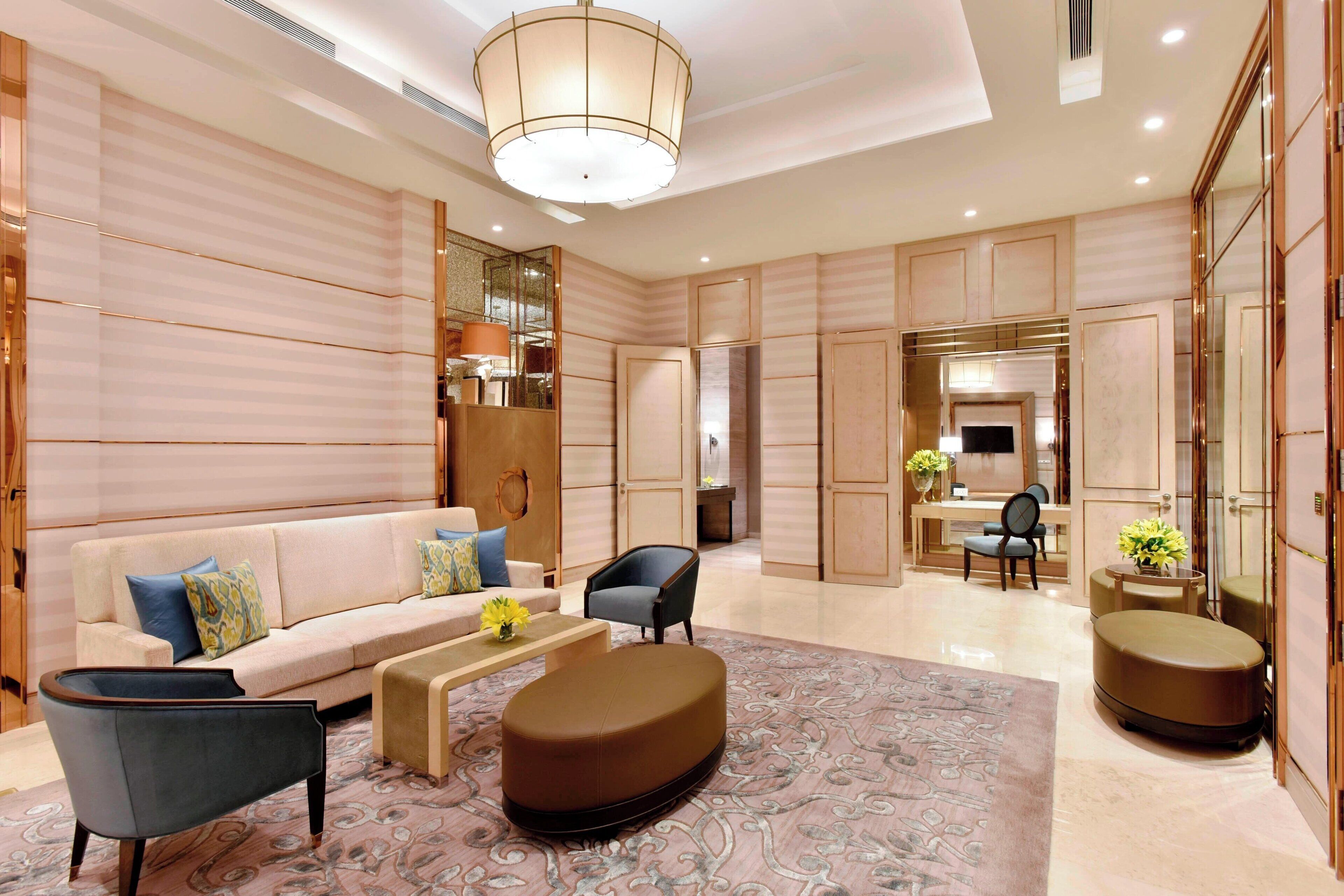 Een moderne hotellobby met een bank, fauteuils, een salontafel en een getextureerd vloerkleed.
