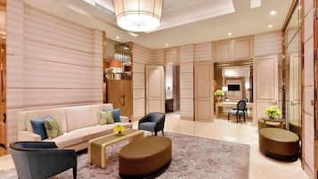 Een moderne hotellobby met een bank, fauteuils, een salontafel en een getextureerd vloerkleed.