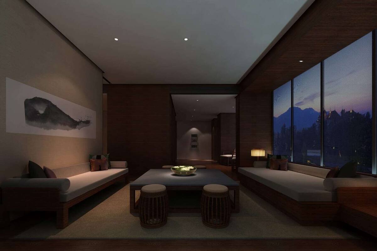A modern interior with a central table, seating areas, and large windows offering a mountain view.