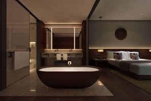 Un baño moderno con una bañera independiente, un tocador con espejo y una cama grande con cabecera.
