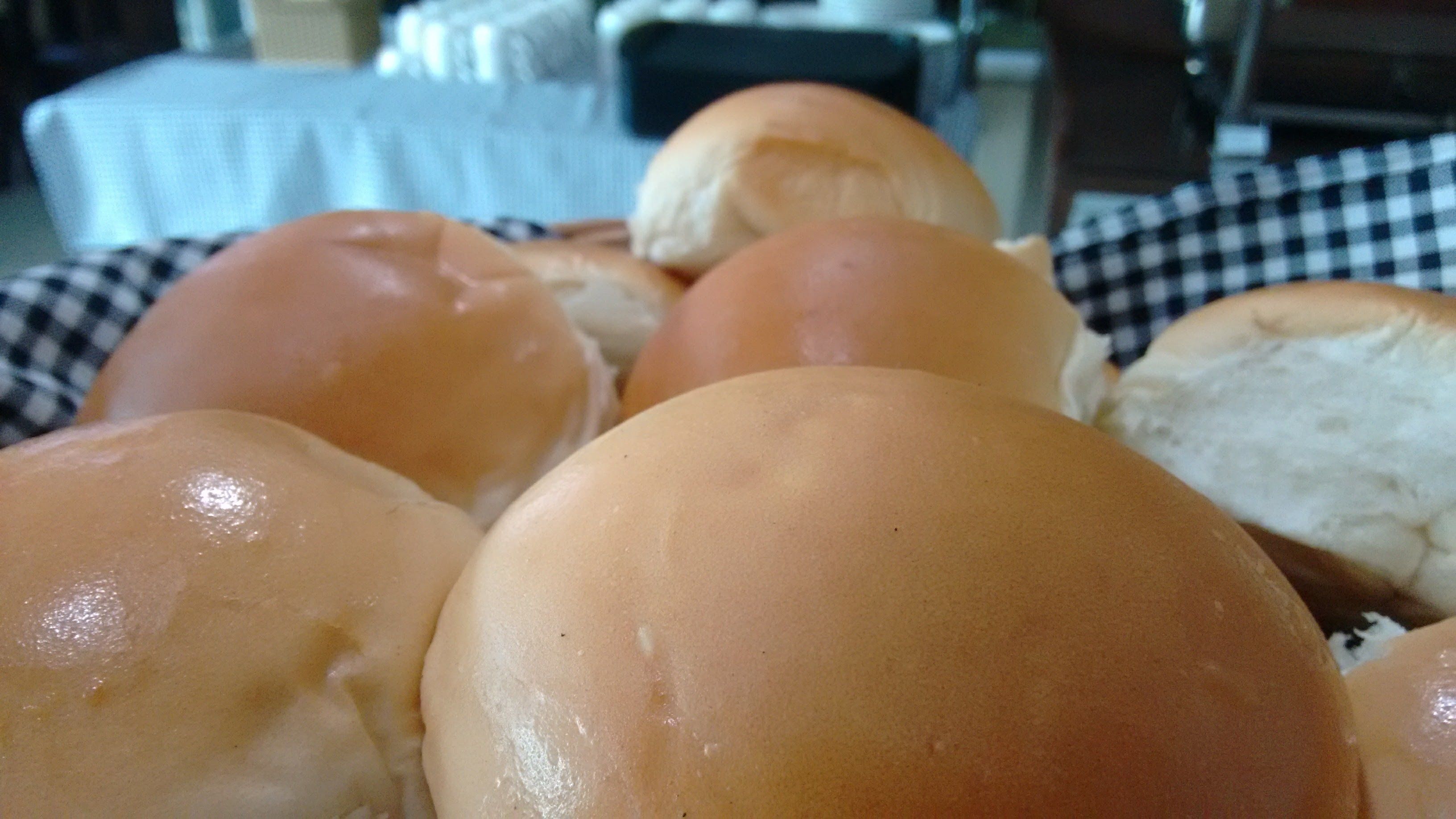 A close-up of several soft, round bread rolls with a shiny, golden-brown crust.