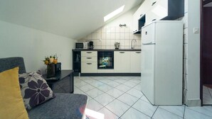 A compact kitchen with white cabinets, a microwave, and a refrigerator.