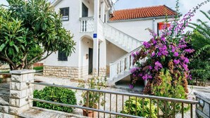 A white building with a red-tiled roof, a staircase, and a balcony.