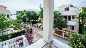 A residential area with a view of the sea, featuring houses with balconies and lush greenery.