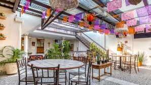 A spacious courtyard with a tiled floor, a central round table, and chairs, surrounded by potted plants and a staircase. - Hotel Boutique Casa Garay (Oaxaca)
