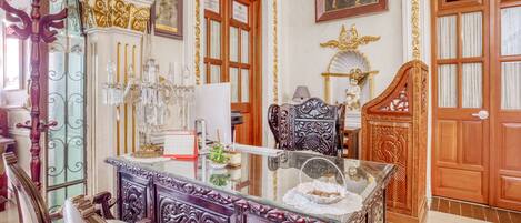A luxurious room with ornate furniture, a glass-top table, and a chandelier.