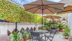An outdoor patio area with a round table and four chairs, surrounded by potted plants and umbrellas. - Hotel Boutique Casa Garay (Oaxaca)