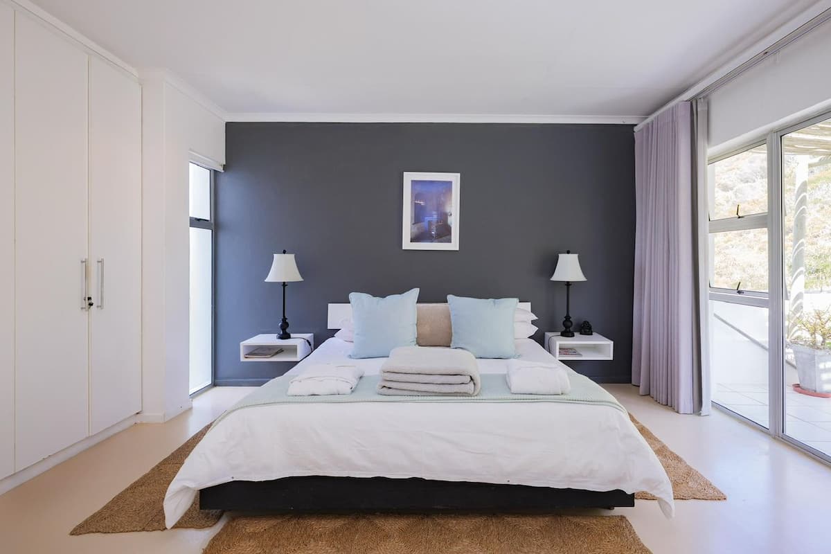 Une chambre à coucher moderne, avec un lit, des tables de chevet, une fenêtre et une vue sur l’extérieur.