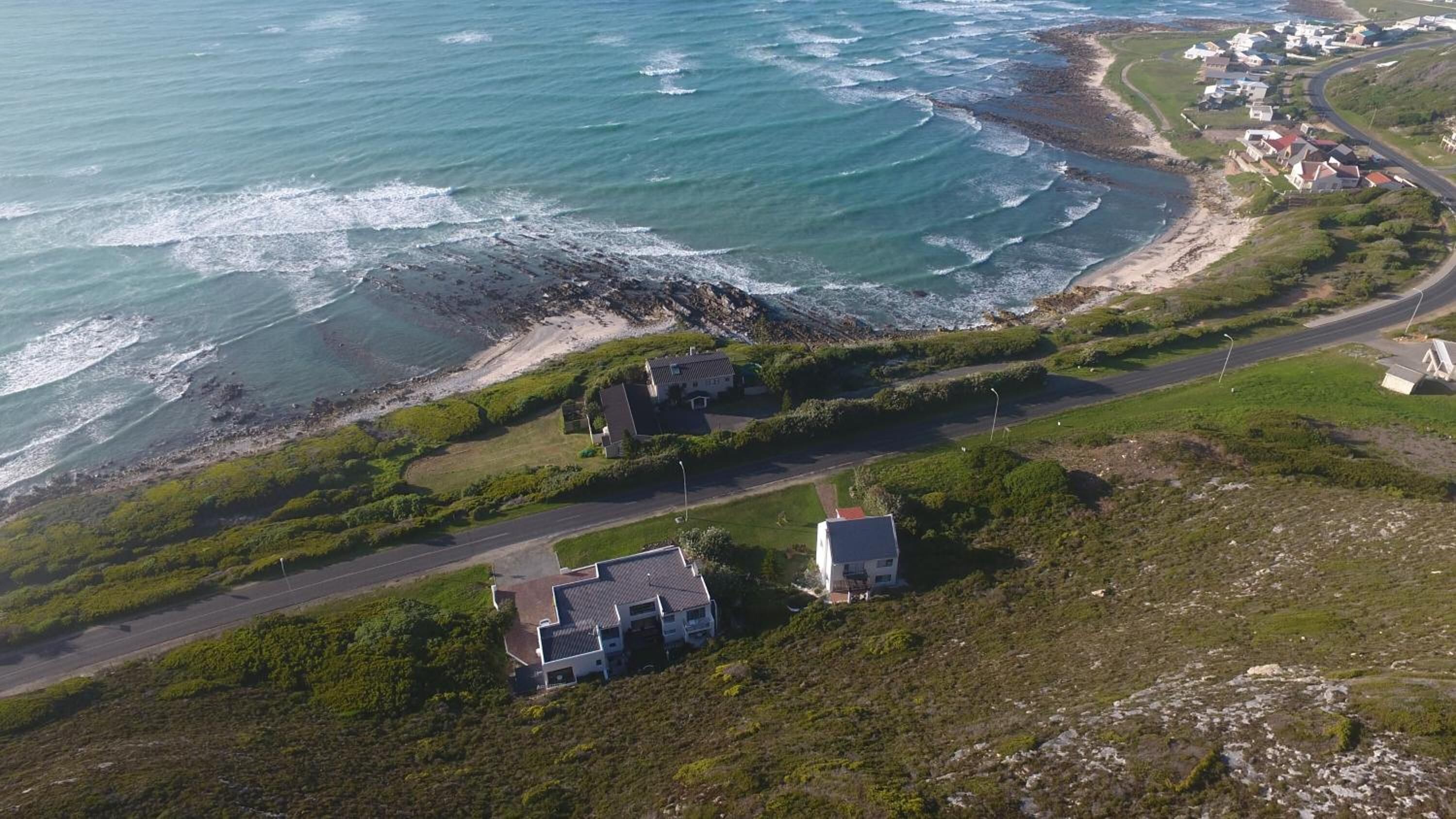 Vista aérea de una zona costera con casas, una carretera y una playa.