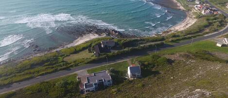 Vista aérea de una zona costera con casas, una carretera y una playa.