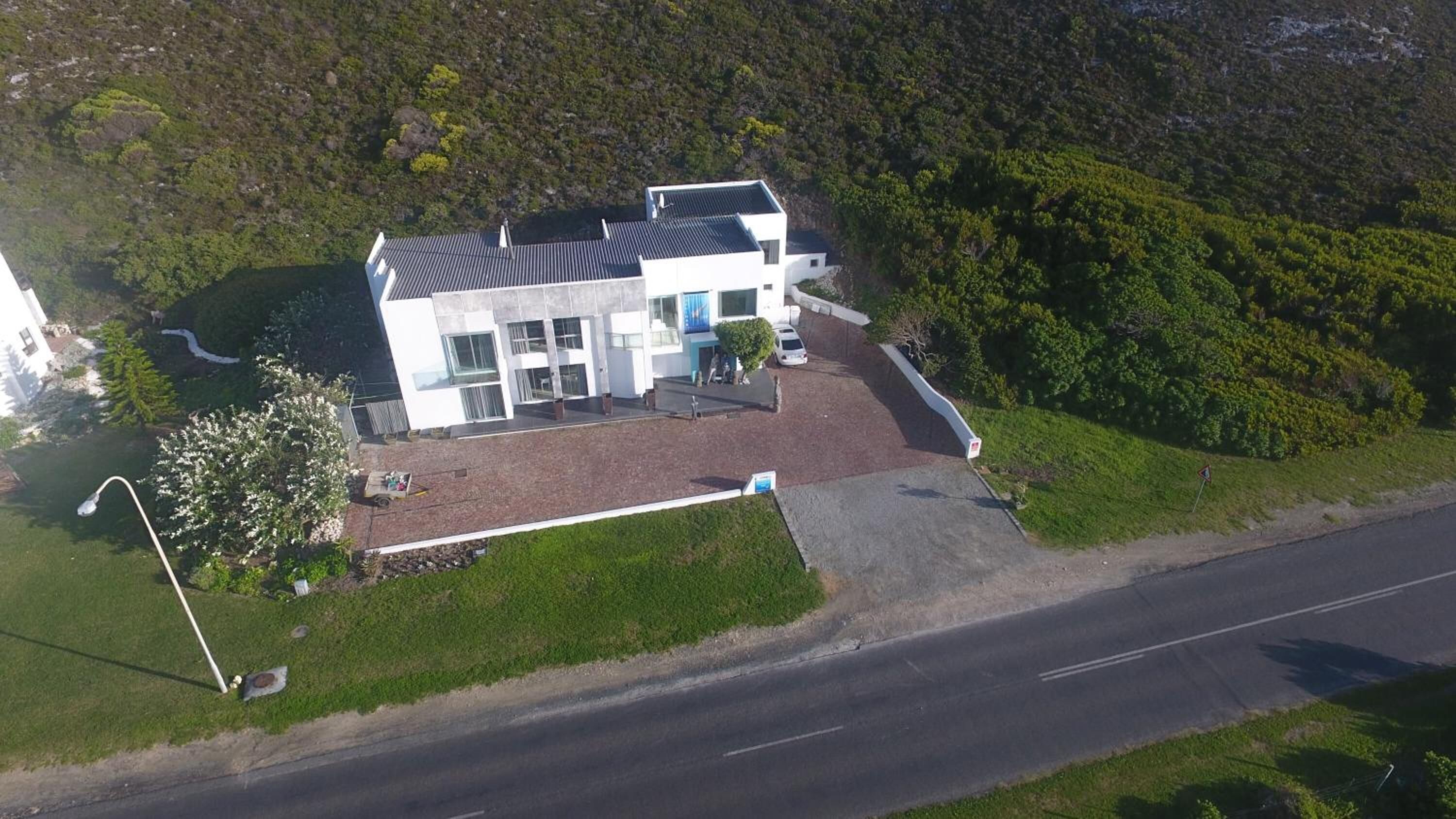 A modern two-story building with a flat roof, large windows, and a paved driveway.
