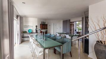 Una cocina moderna con una mesa de comedor de vidrio, asientos tapizados a rayas y una escalera con barandilla de metal.