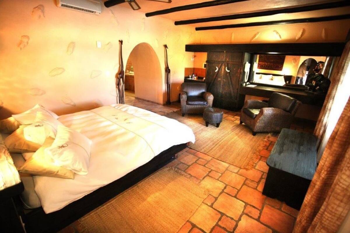Un dormitorio con una cama grande, dos sillones, una mesita y un armario.