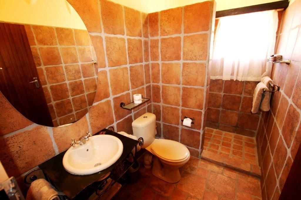 A bathroom with a stone-tiled wall, a sink, a toilet, and a towel rack.