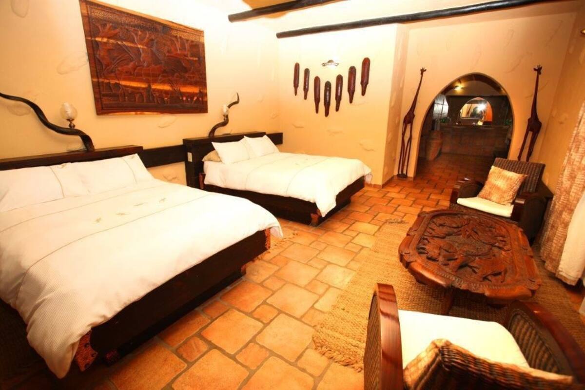 Una habitación con dos camas, una mesita de madera y una pared decorada.